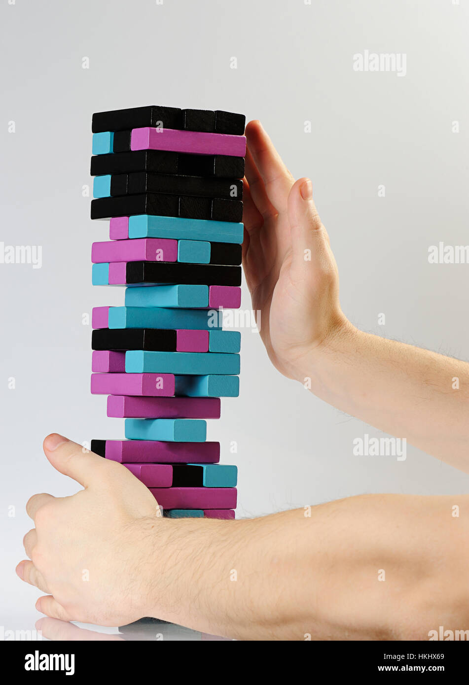 hands hold fall tower color jenga on white Stock Photo