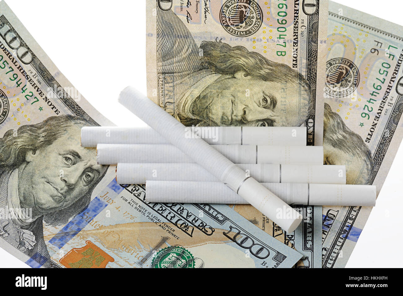 cigarettes lay on top of dollars isolated white Stock Photo