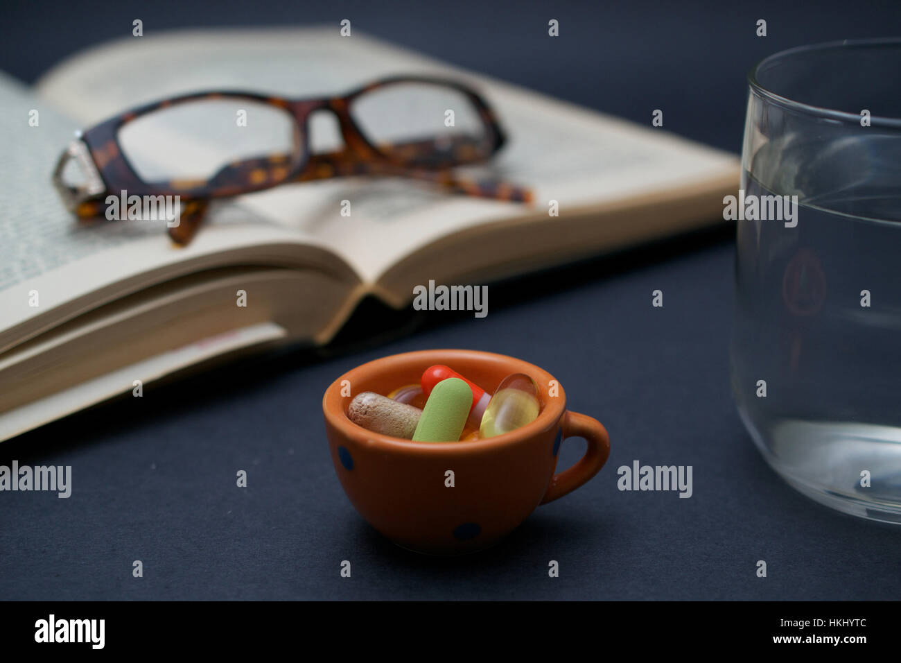 A pair of broken reader glasses resting on an old open book, a bunch of