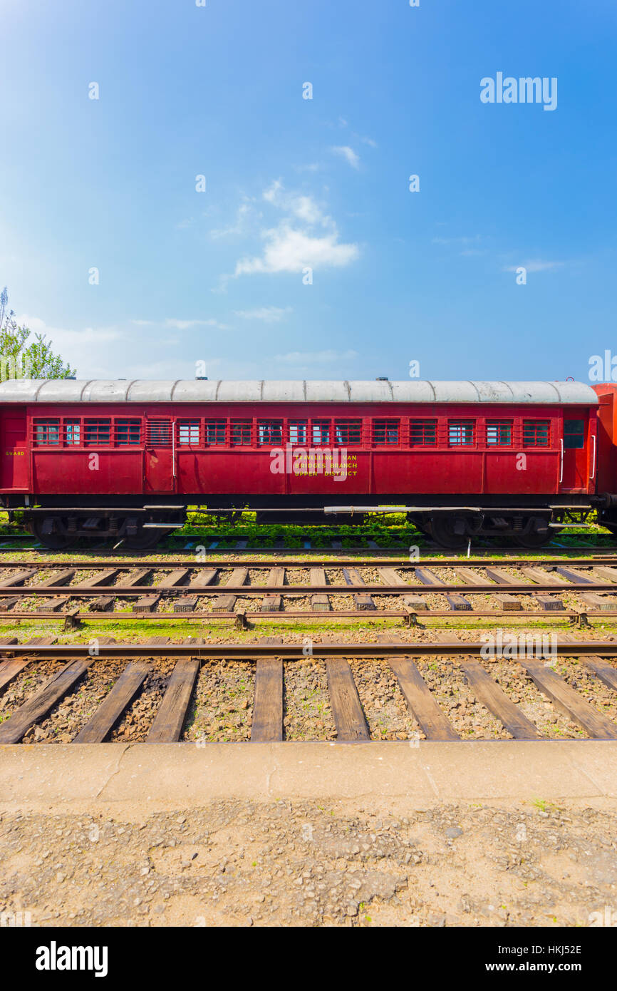 Side view of an old stationary red passenger carriage car sitting parked on train tracks, part of Sri Lanka Railways Stock Photo