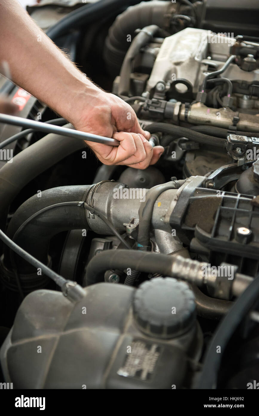 Close up of incognito mechanic hands holding a tool while working on car engine Stock Photo