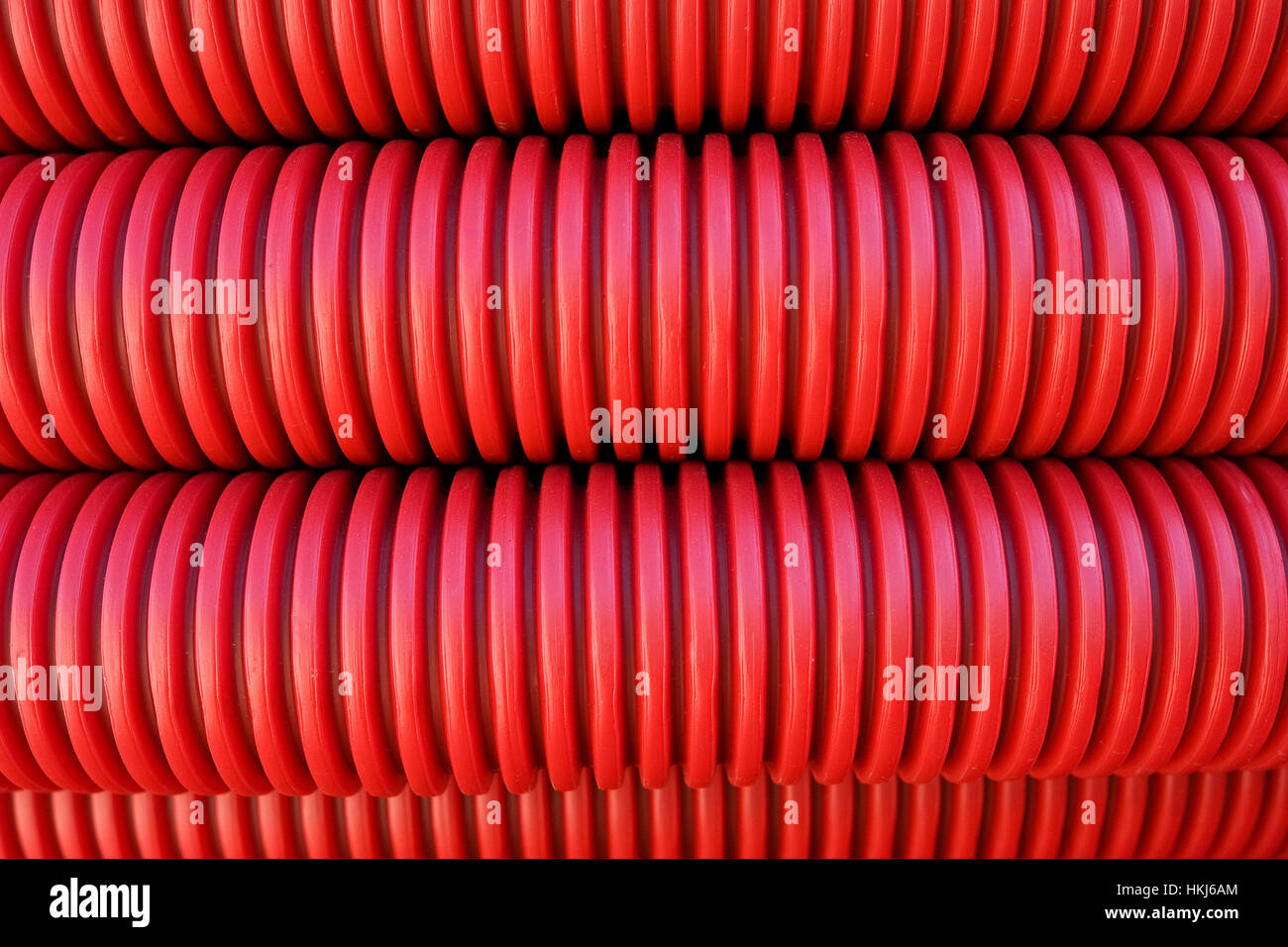 Laying close to each other corrugated red plastic pipes. Ribbed drains