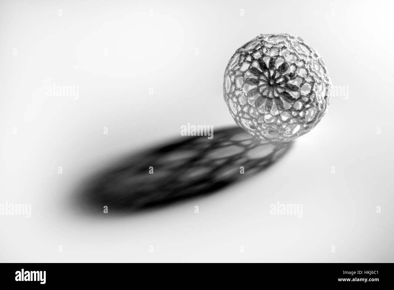 Single openwork sphere ball casting long shadow isolated on white background Stock Photo