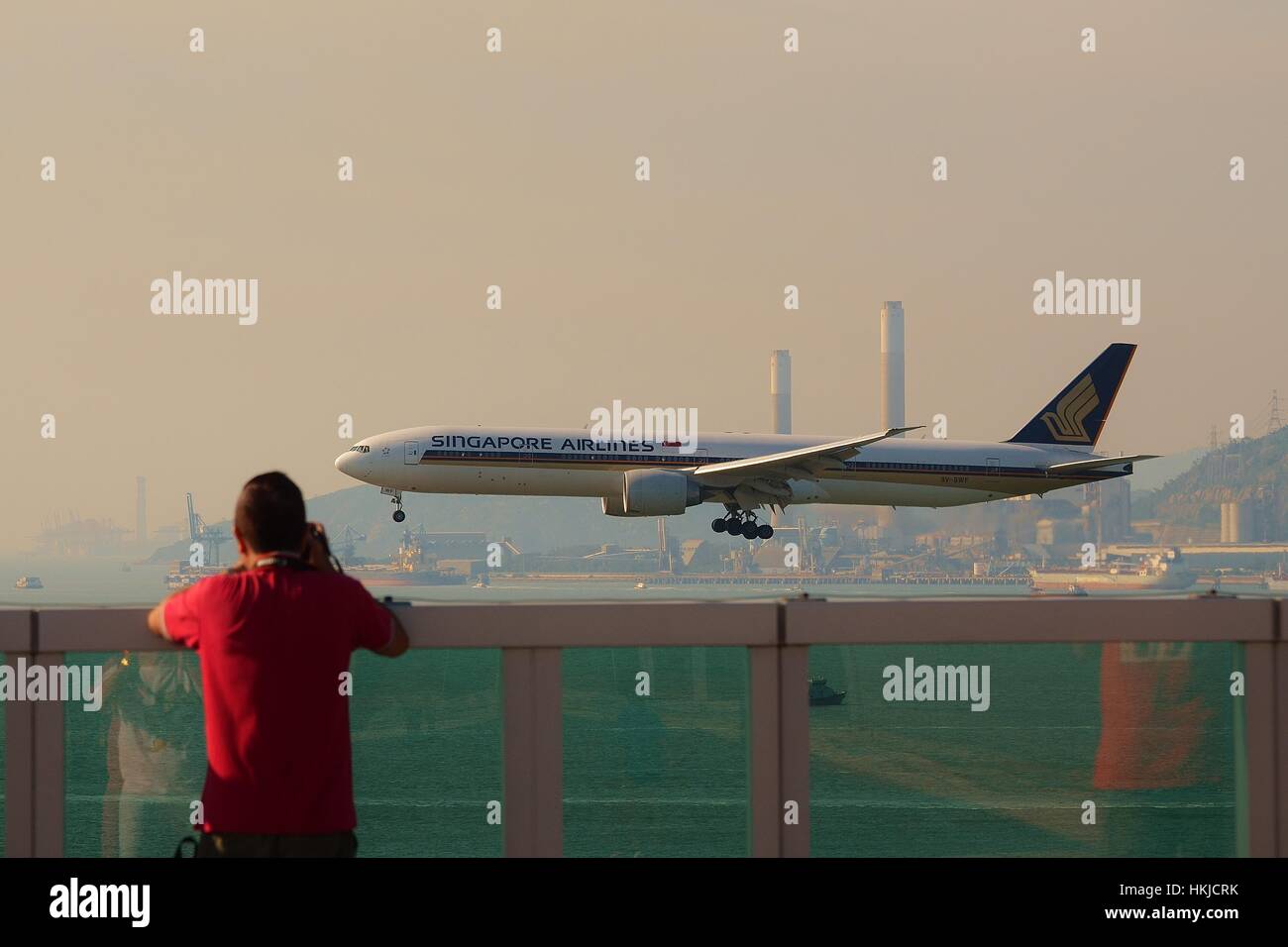 A Planespotter is taking photo of Singapore Airlines Boeing 777-300ER 9V-SWF landing at Hong Kong International Airport Stock Photo