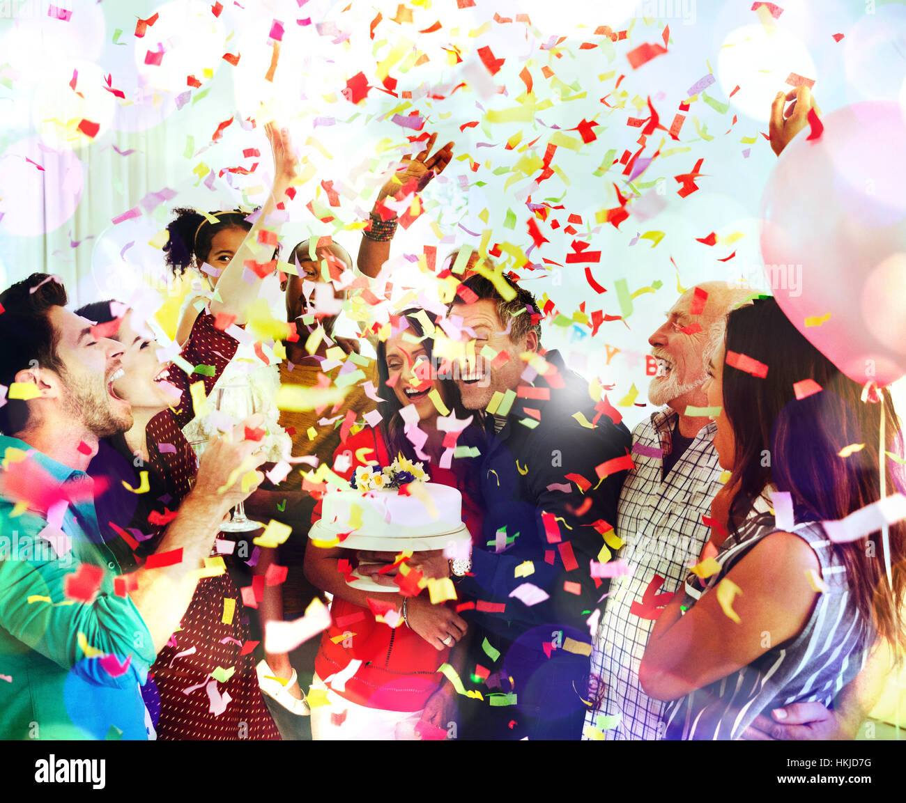 Family throwing confetti celebrating birthday party with cake Stock