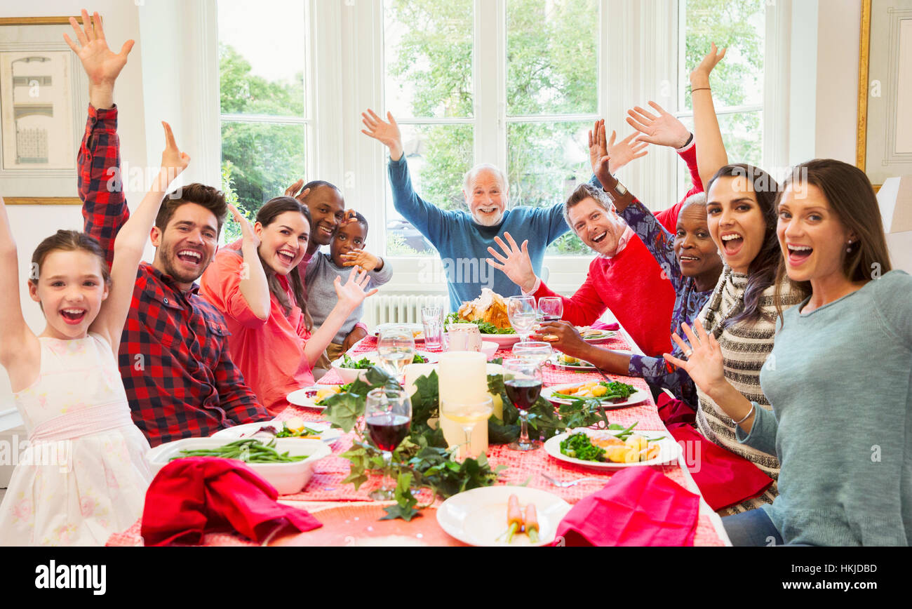 Portrait enthusiastic multi-ethnic multi-generation family waving at Christmas dinner table Stock Photo