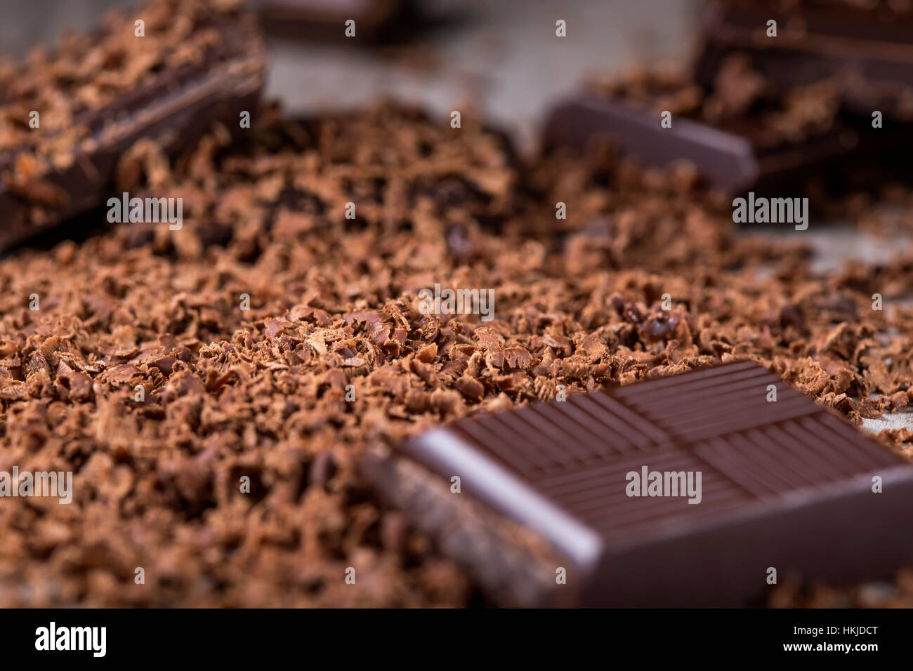 Pile of grated chocolate and broken piece of dark chocolate on wooden rustic background Stock Photo