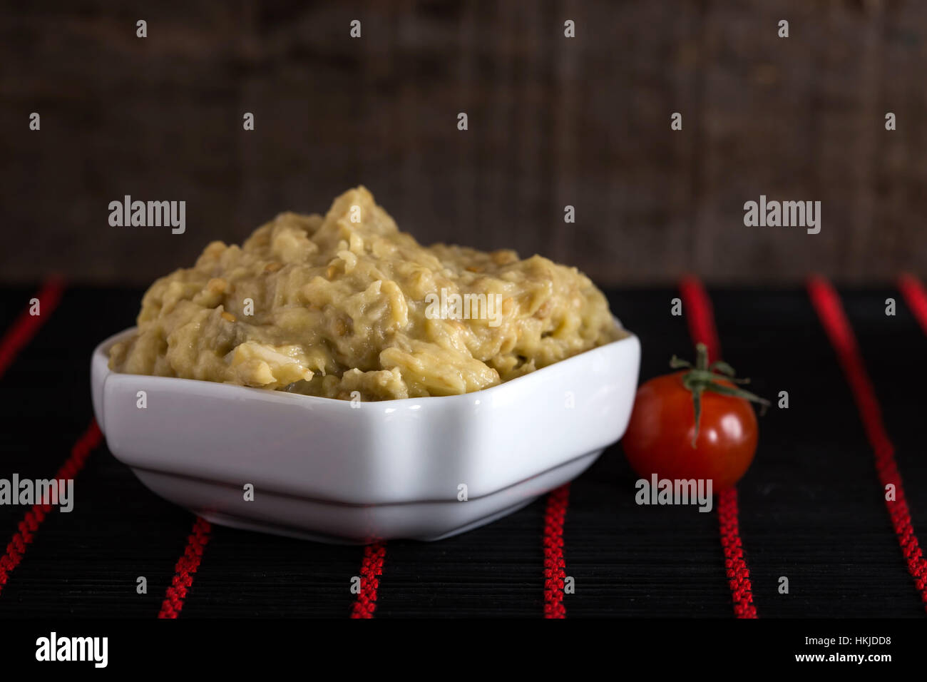 Eggplant salad with mayonnaise and onion and one cherry tomato on rug Stock Photo