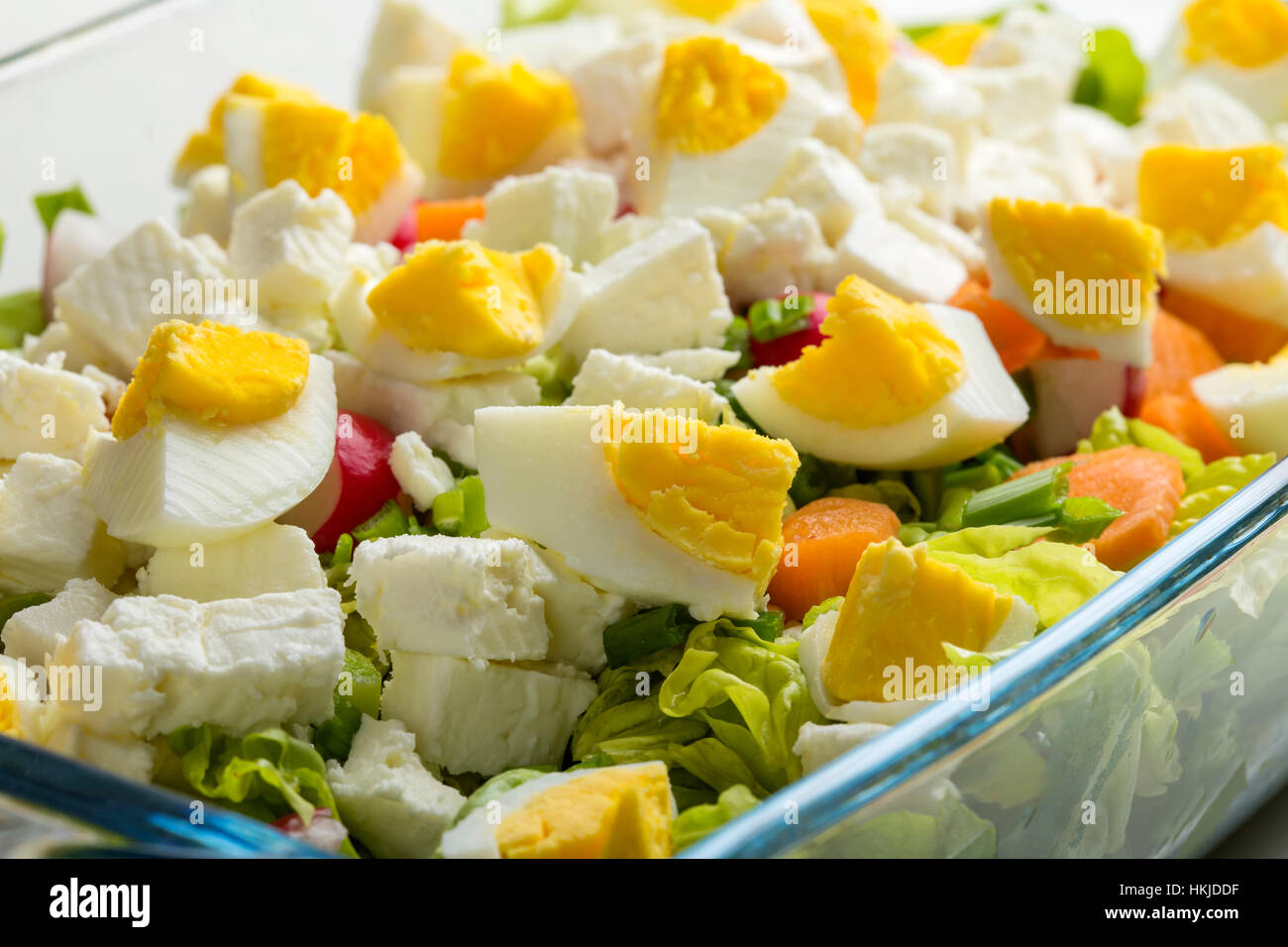 Salad with eggs, feta cheese and carrot in transparent glass bowl Stock Photo