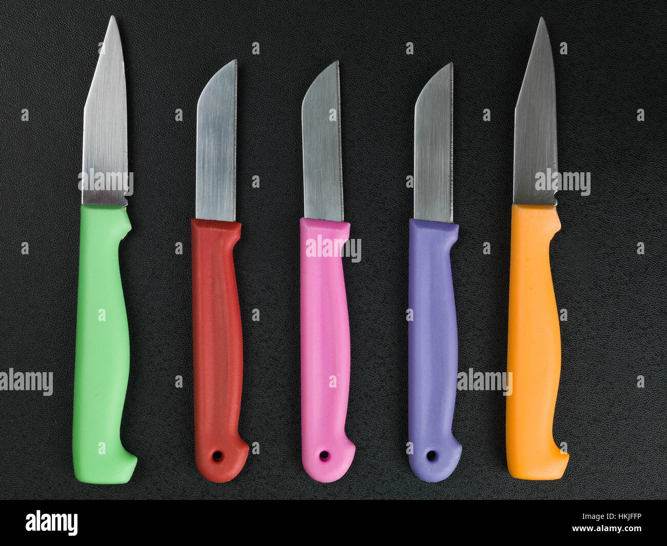 Set of Colorful Kitchen Knives Against a Black Background Stock Photo