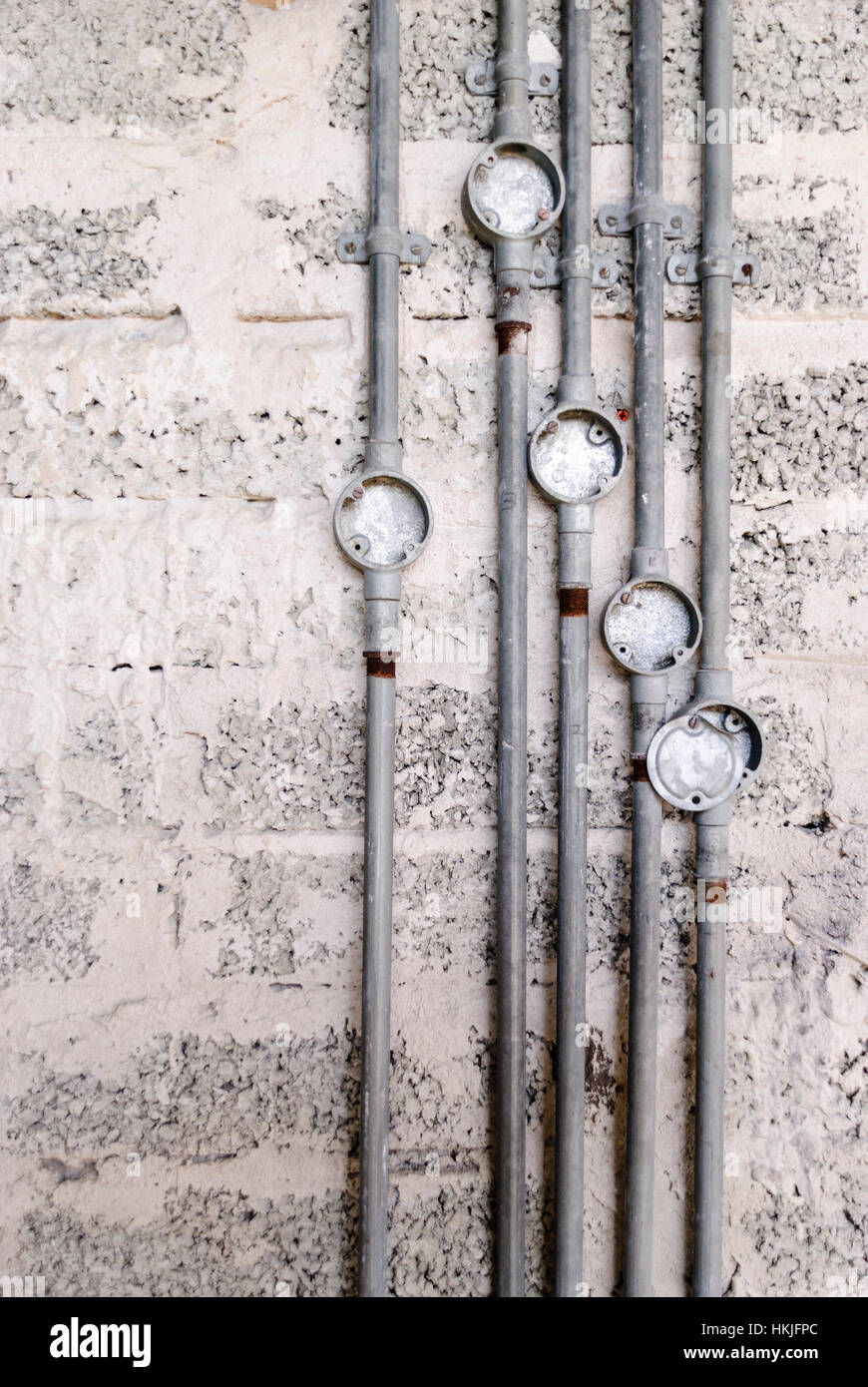 Metal electrical conduit on a bare breeze block wall at a building site