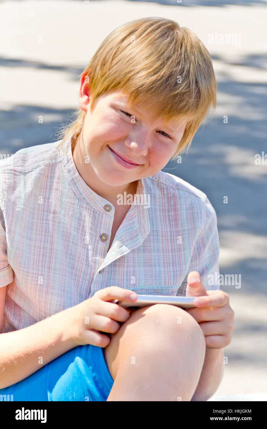 Blonde smiling boy with cellular phone in summer Stock Photo