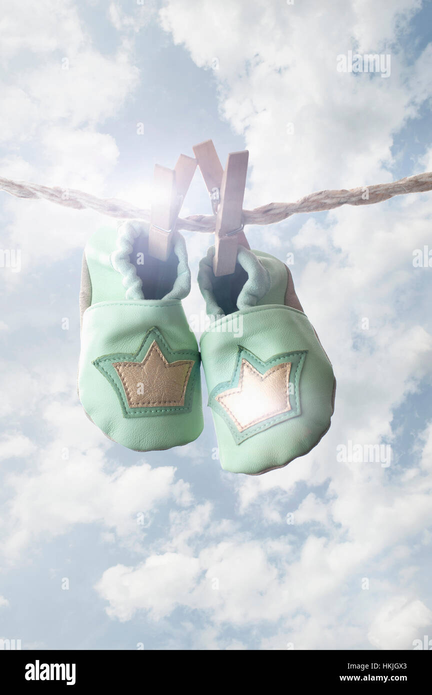Three pairs of baby shoes hanging on clothes line in sun, Bavaria, Germany Stock Photo
