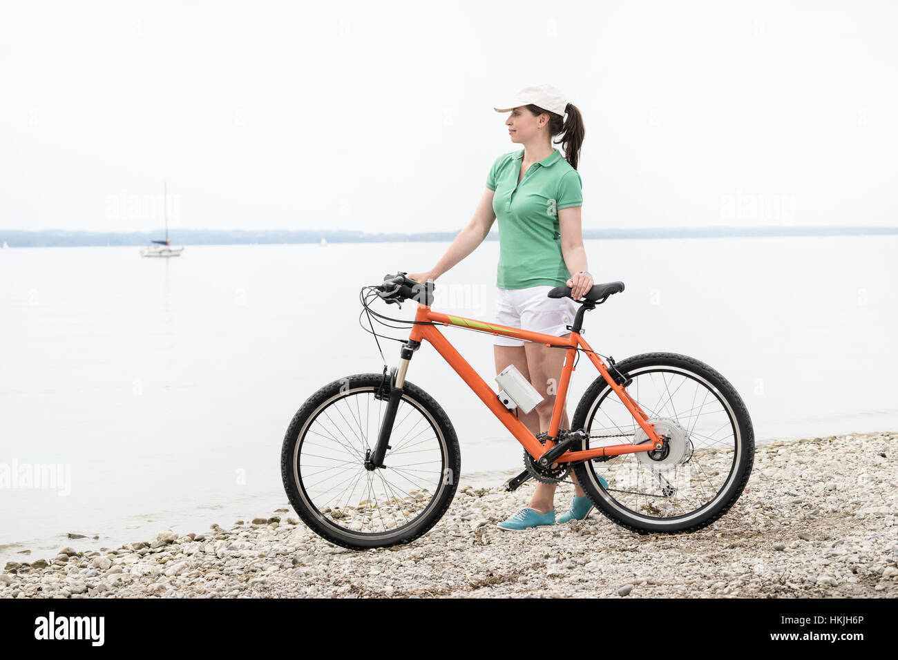 Mature woman with electric bicycle at lakeshore, Bavaria, Germany Stock Photo