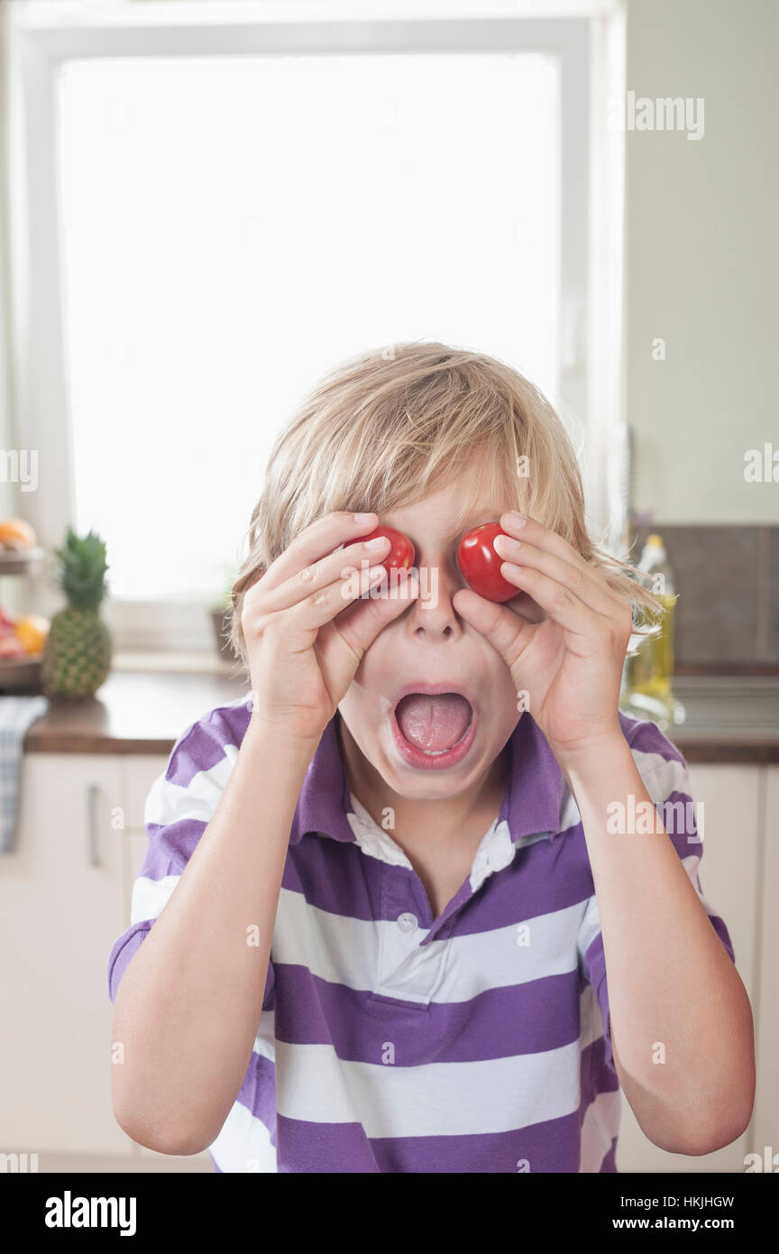 Playful boy making face with tomatoes,Bavaria,Germany Stock Photo