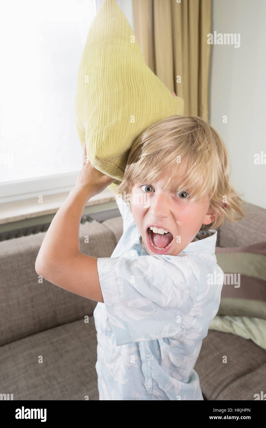 Boy shouting while pillow fighting in living room,Bavaria,Germany Stock Photo