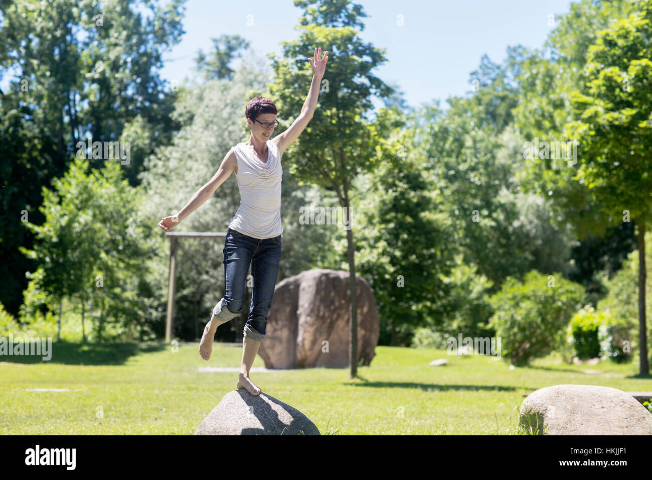 Mature woman standing on one leg on rock, Freiburg im Breisgau, Baden-Württemberg, Germany Stock Photo