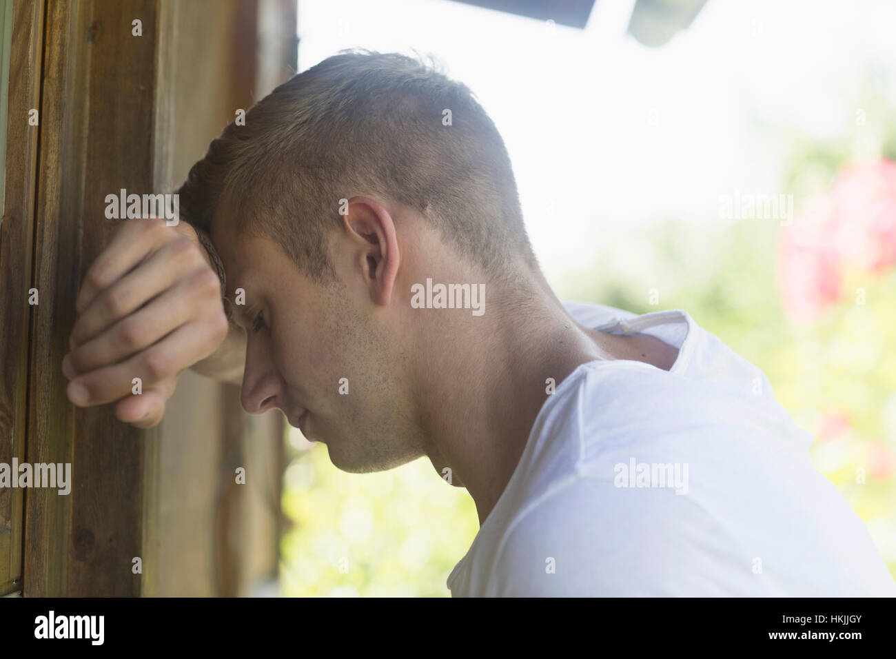 Young man leaning head to wall in sorrow, Freiburg im Breisgau, Baden-Württemberg, Germany Stock Photo