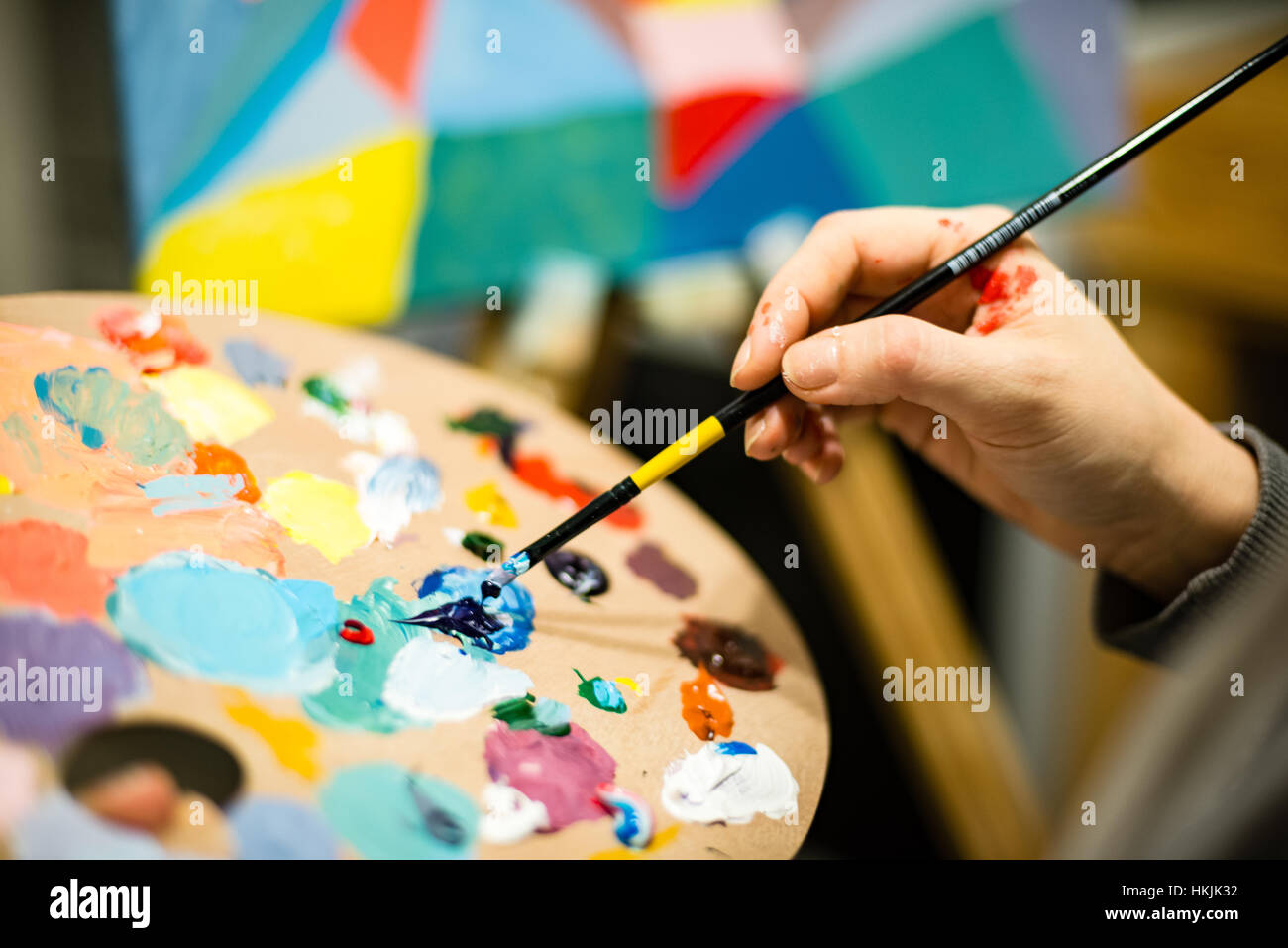 artist painting with acrylic colors and mixing tones on the pallet