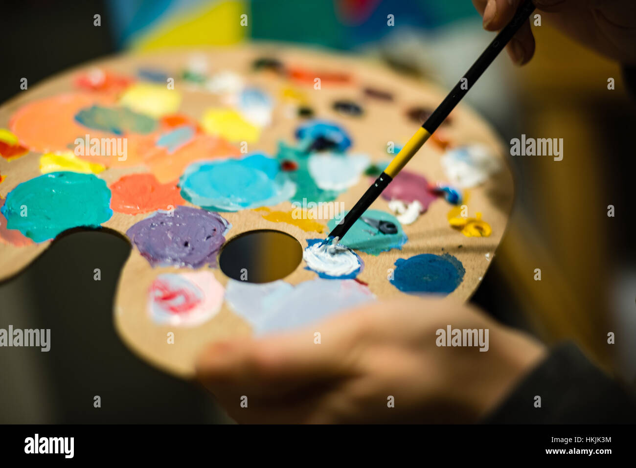 artist painting with acrylic colors and mixing tones on the pallet