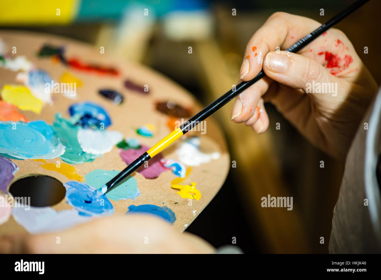 artist painting with acrylic colors and mixing tones on the pallet