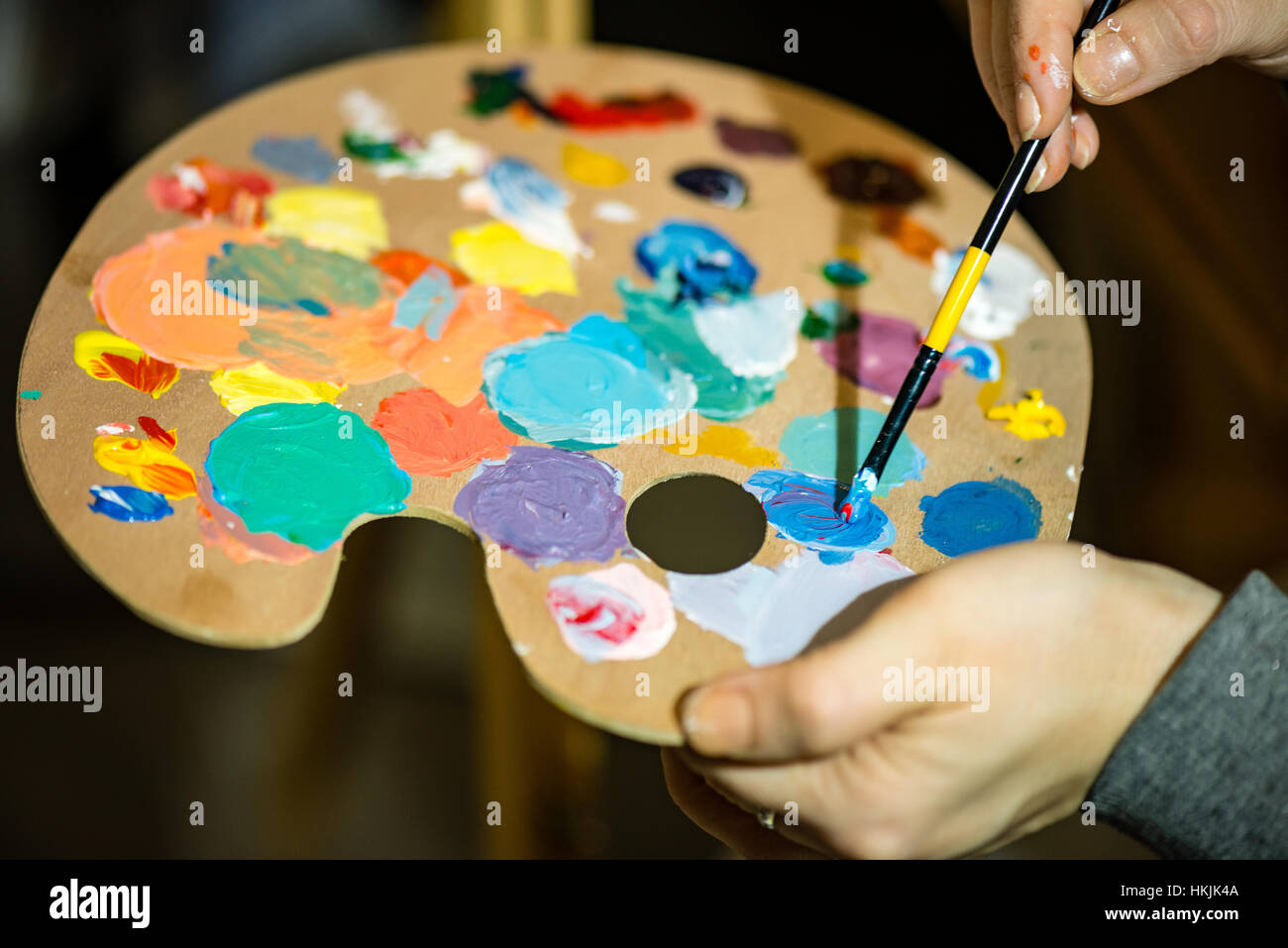 artist painting with acrylic colors and mixing tones on the pallet