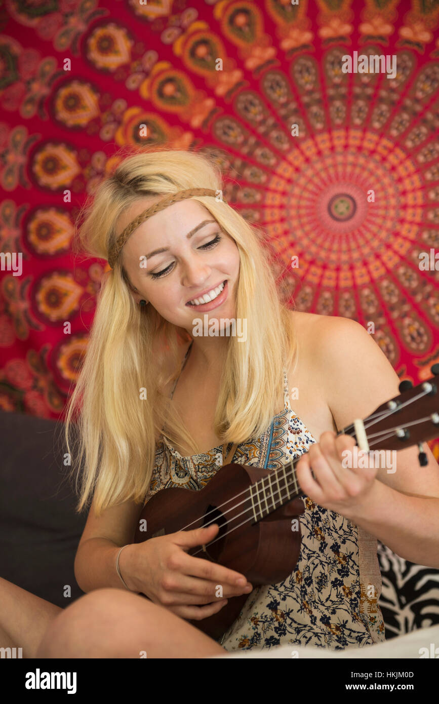 Young woman playing ukulele in the bedroom, Bavaria, Germany Stock