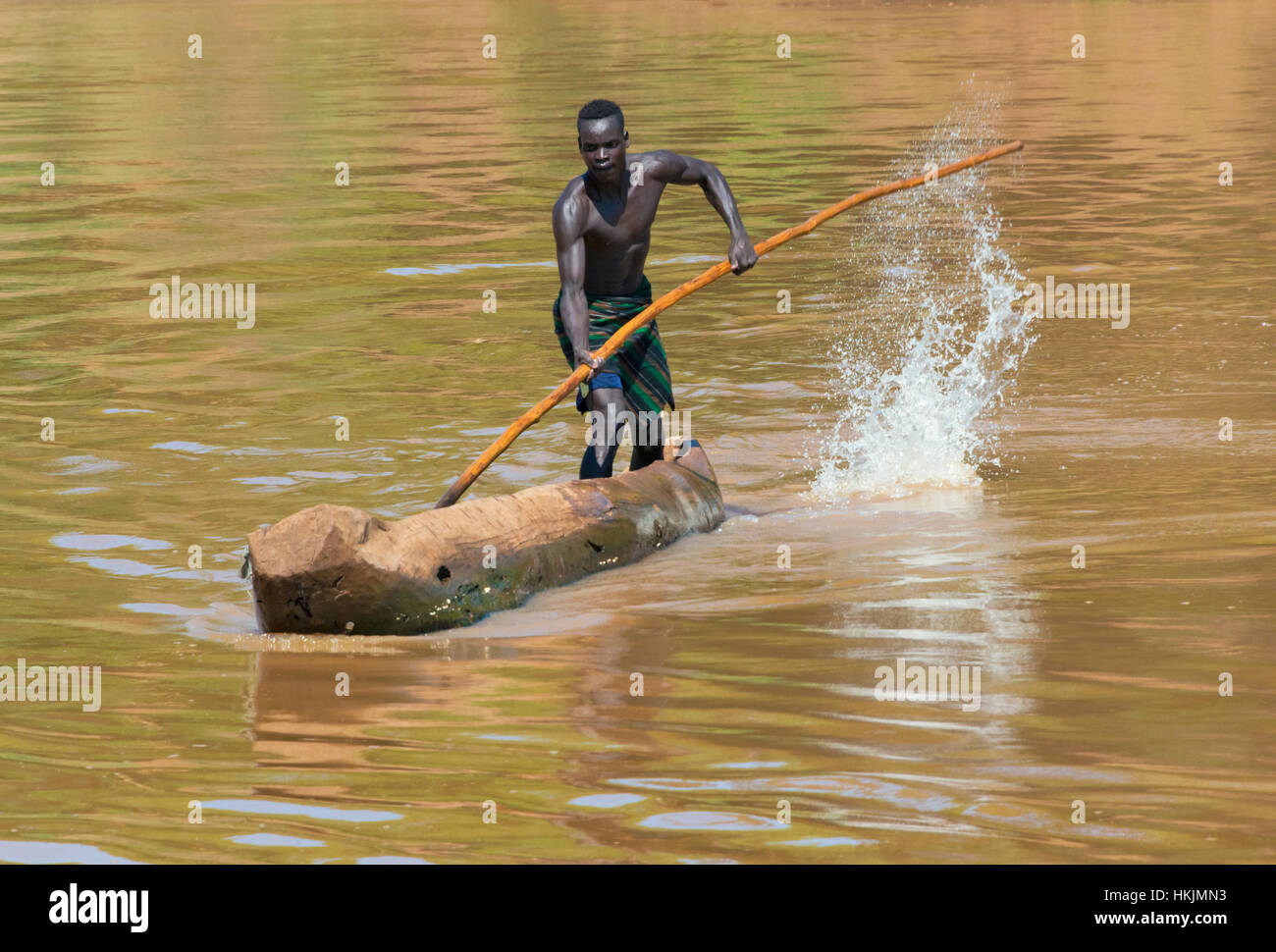 Kara tribe man paddling a dugout canoe on Lower Omo River, South Omo, Ethiopia Stock Photo