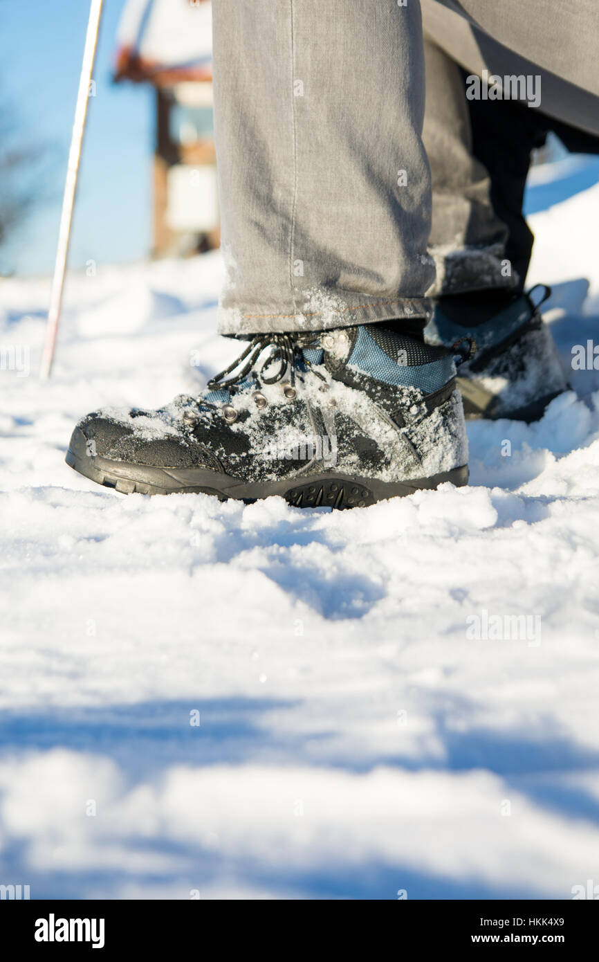 Snow covered winter boots and hiking stick Stock Photo