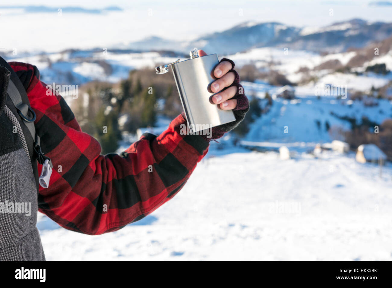 Male hand holding hip flask on a snowy mountain top Stock Photo