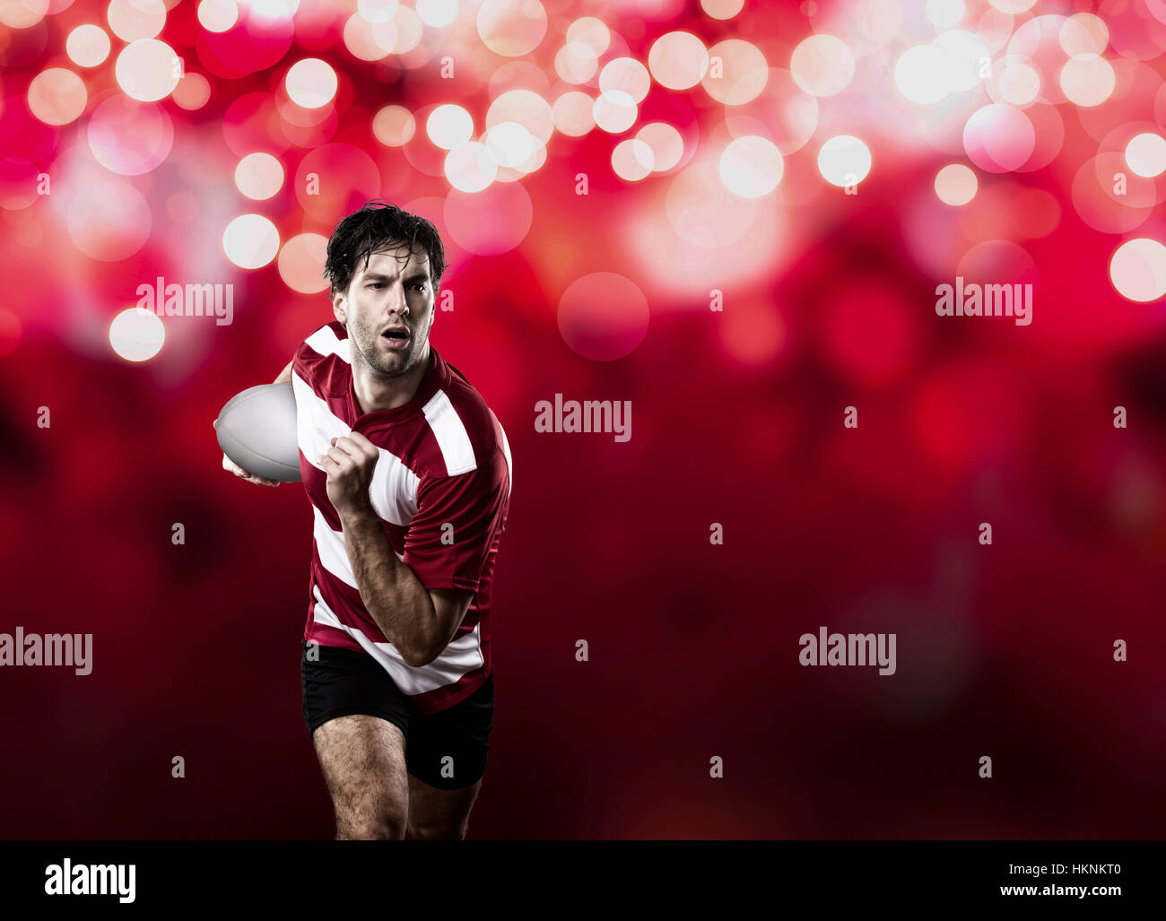 Rugby player in a red uniform running on a red lights background Stock ...