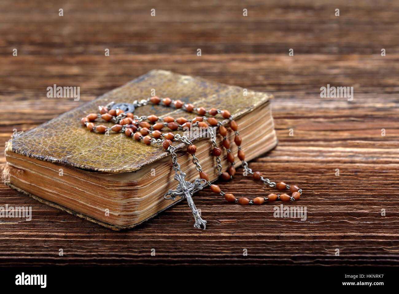Very old prayer book and vintage rosary on wooden background with empty