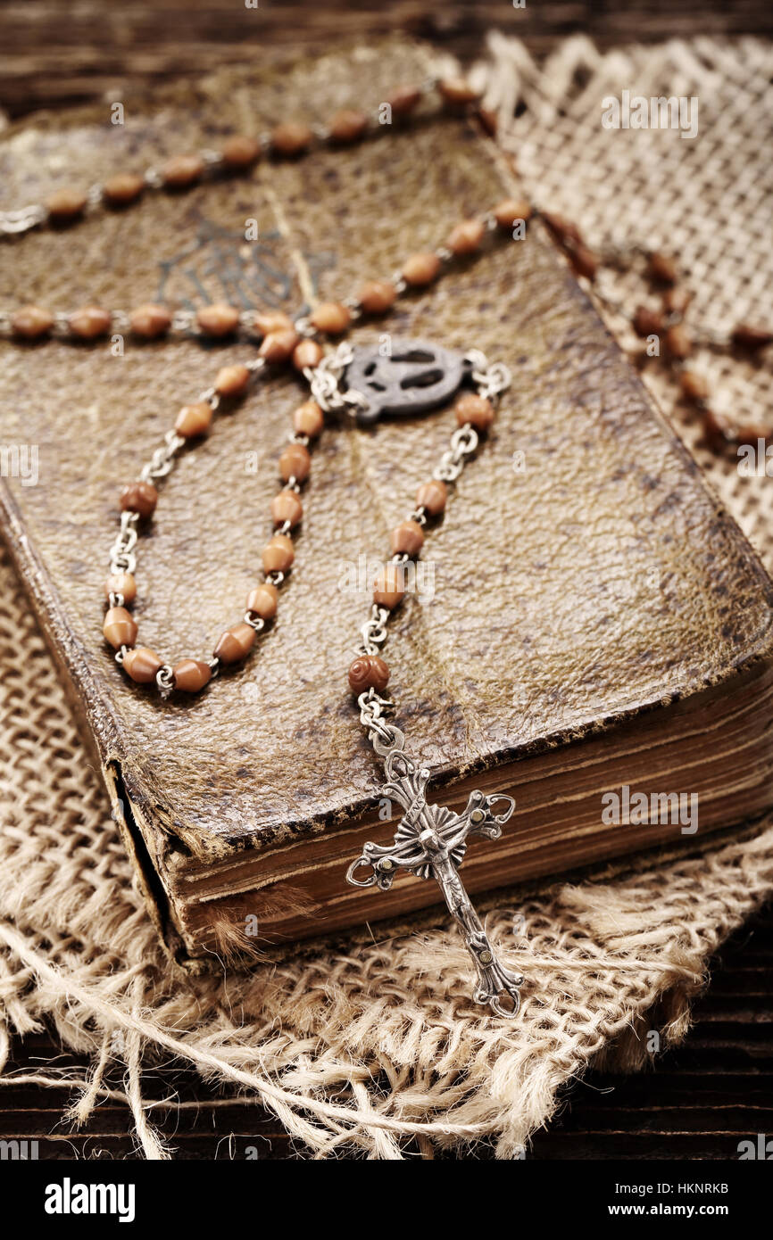 Very old prayer book and vintage rosary on wooden background Stock