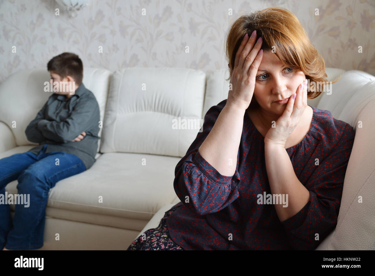 Mother and son after quarrel sit on couch Stock Photo