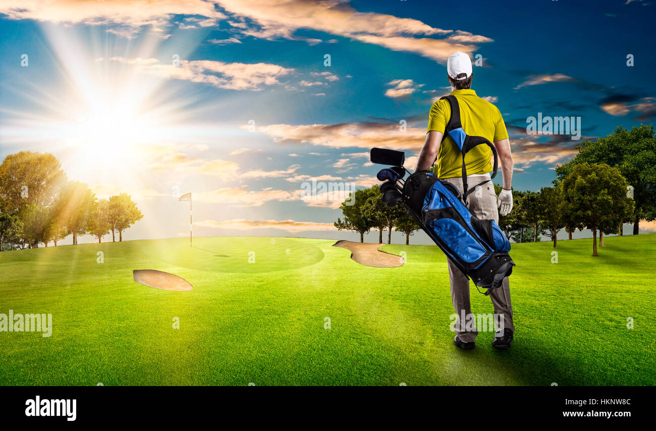 Golf Player in a yellow shirt walking with a bag of golf clubs on his