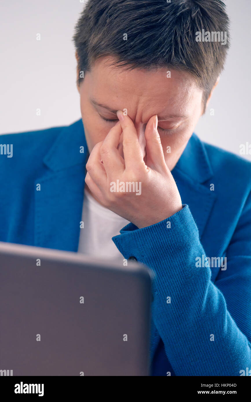 Exhausted businesswoman working overtime on office laptop computer, hand on the forehead Stock Photo