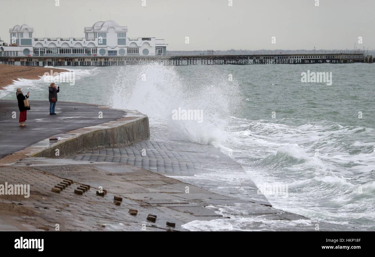 Members of the public take photographs of waves crashing into South Parade Pier in Southsea, Hampshire. Stock Photo