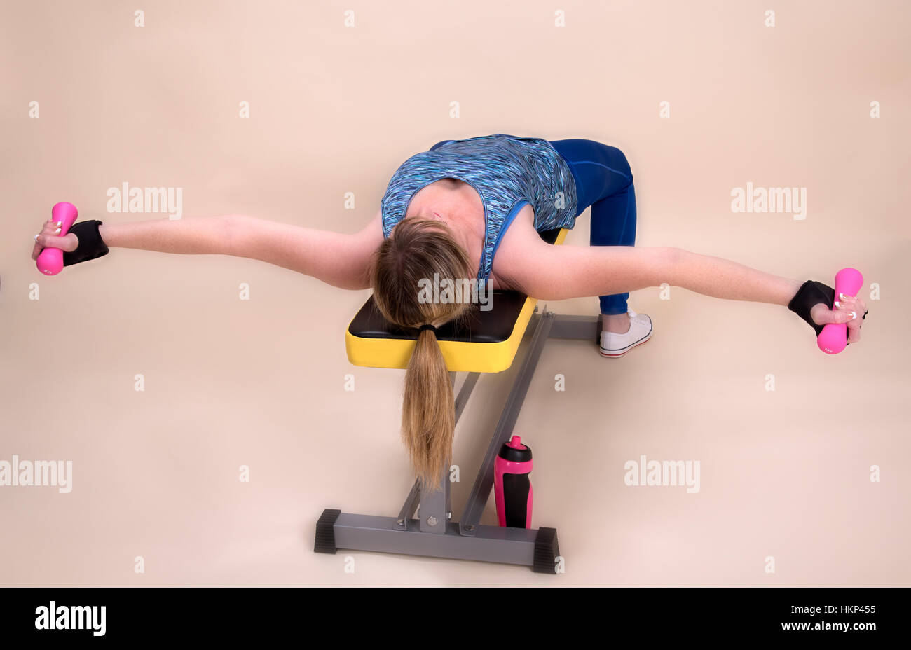 Woman laying on a bench using weights in a gym Stock Photo