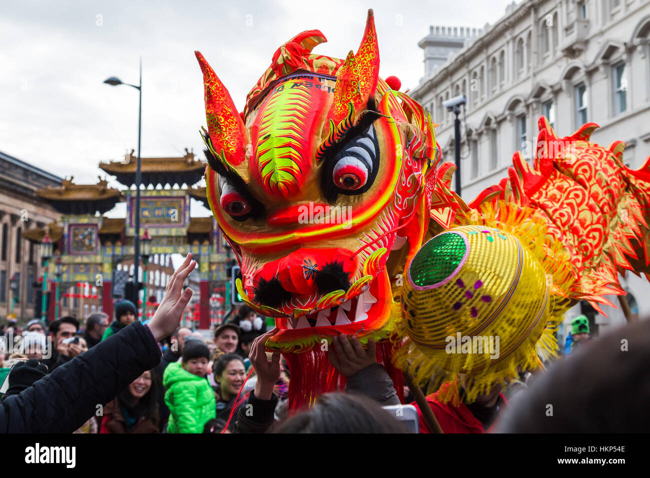The dragon dance slows the pace down as it takes a moment to meet the crowds on the streets of Liverpool during Chinese New Year celebrations Stock Photo