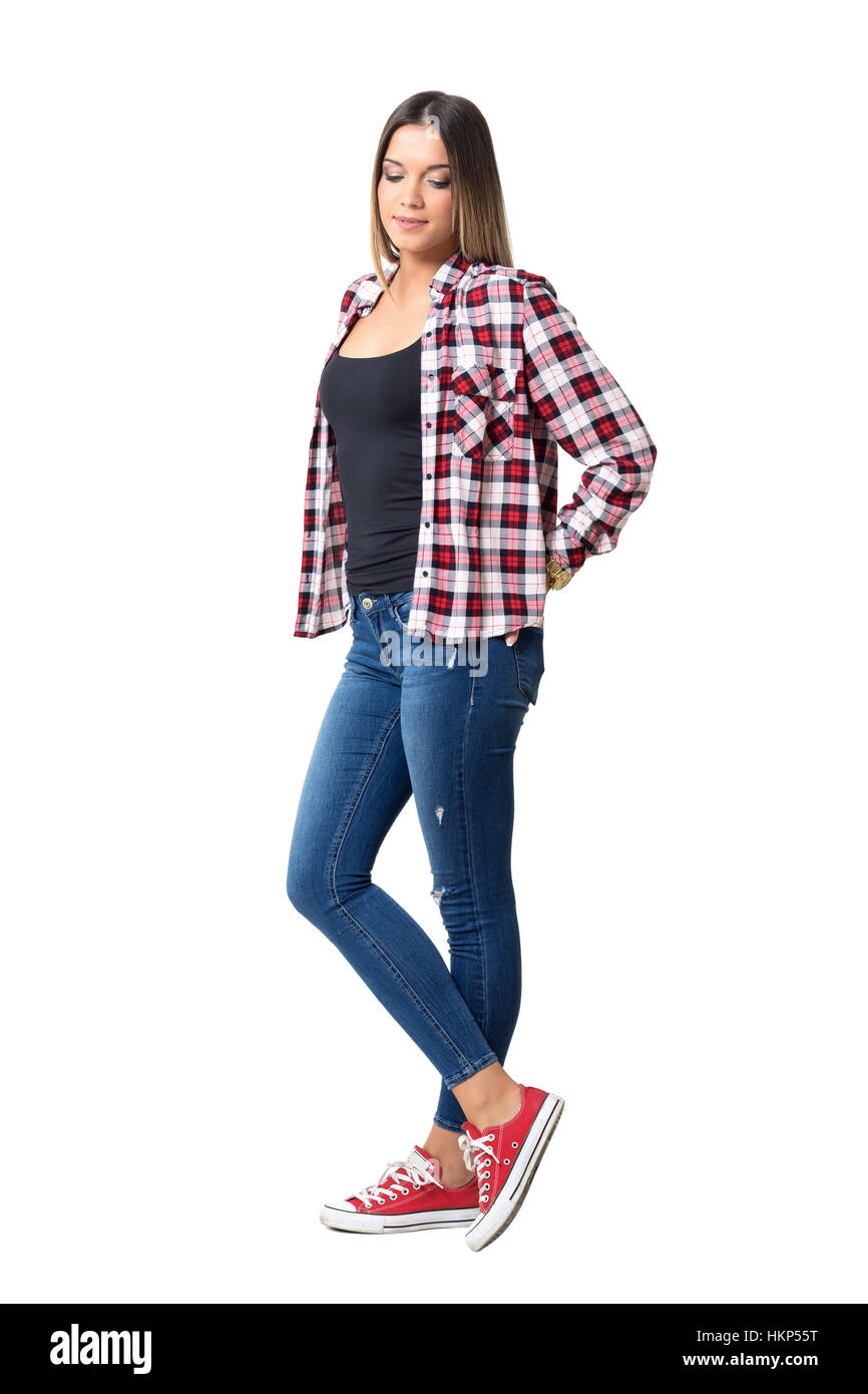 Beautiful shy casual girl wearing jeans, red and white plaid shirt and sneakers looking down. Full body length portrait isolated Stock Photo