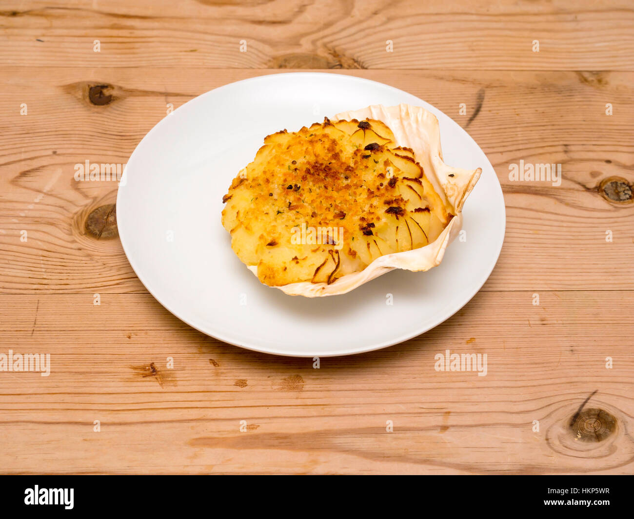 Coquilles St Jacques single serving white plate wooden table Stock