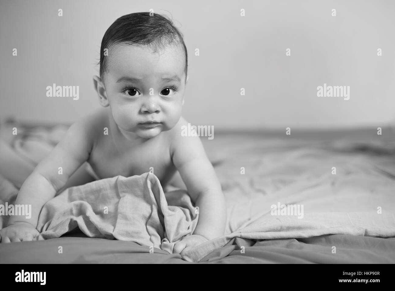 black and white photo of small baby on bed Stock Photo