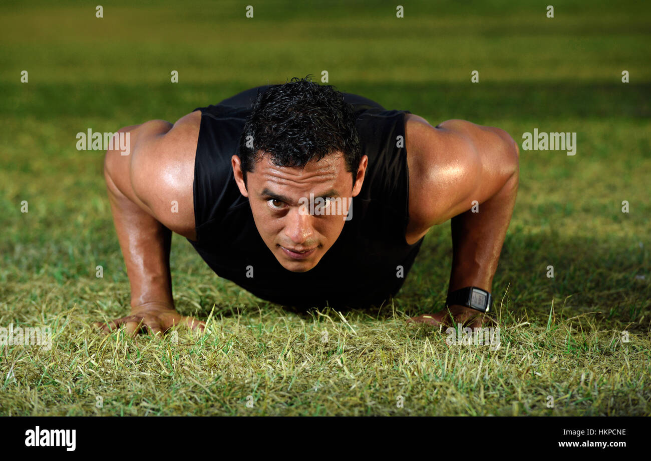 close up man doing push up on green grass Stock Photo
