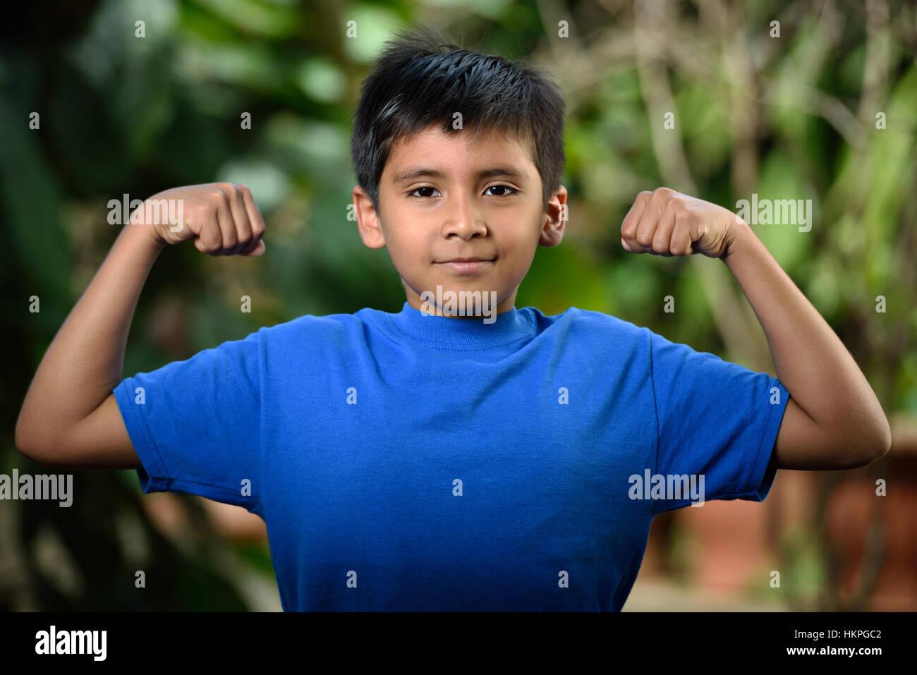 latino boy show muscles in green garden Stock Photo