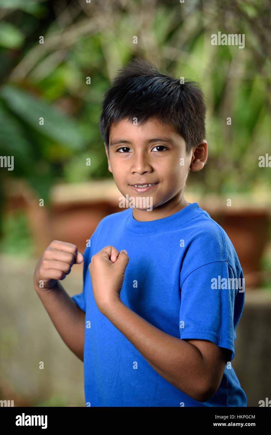 latino little boy with fist in green garden Stock Photo