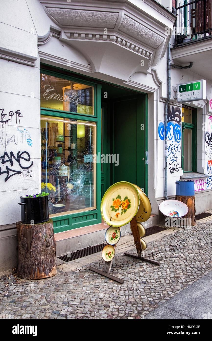 Berlin, Prenzlauer Berg. Liv Emaille shop selling old enamel household goods , vandalised with broken display window & graffiti Stock Photo