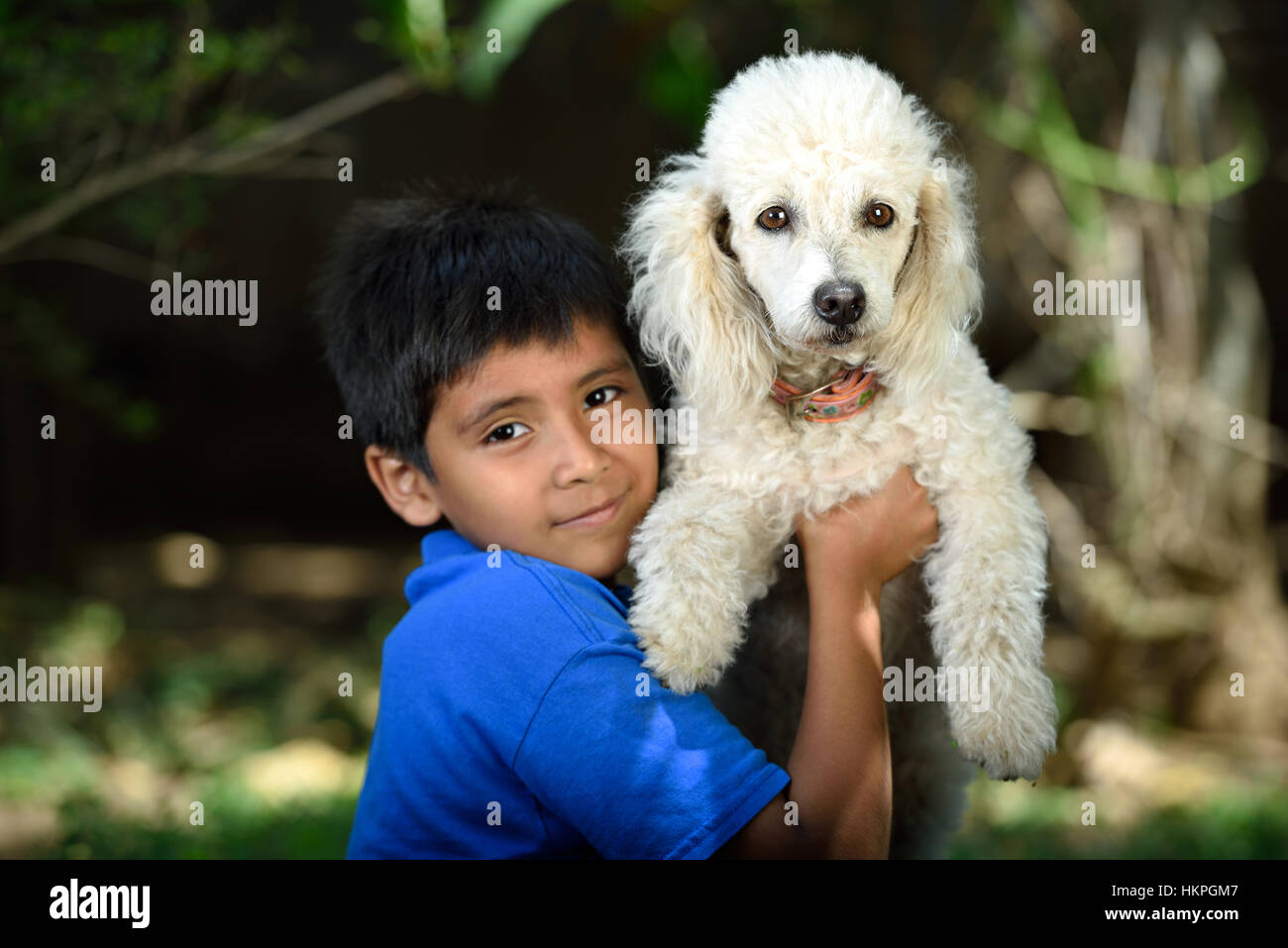 white poodle friend of little boy in green park Stock Photo