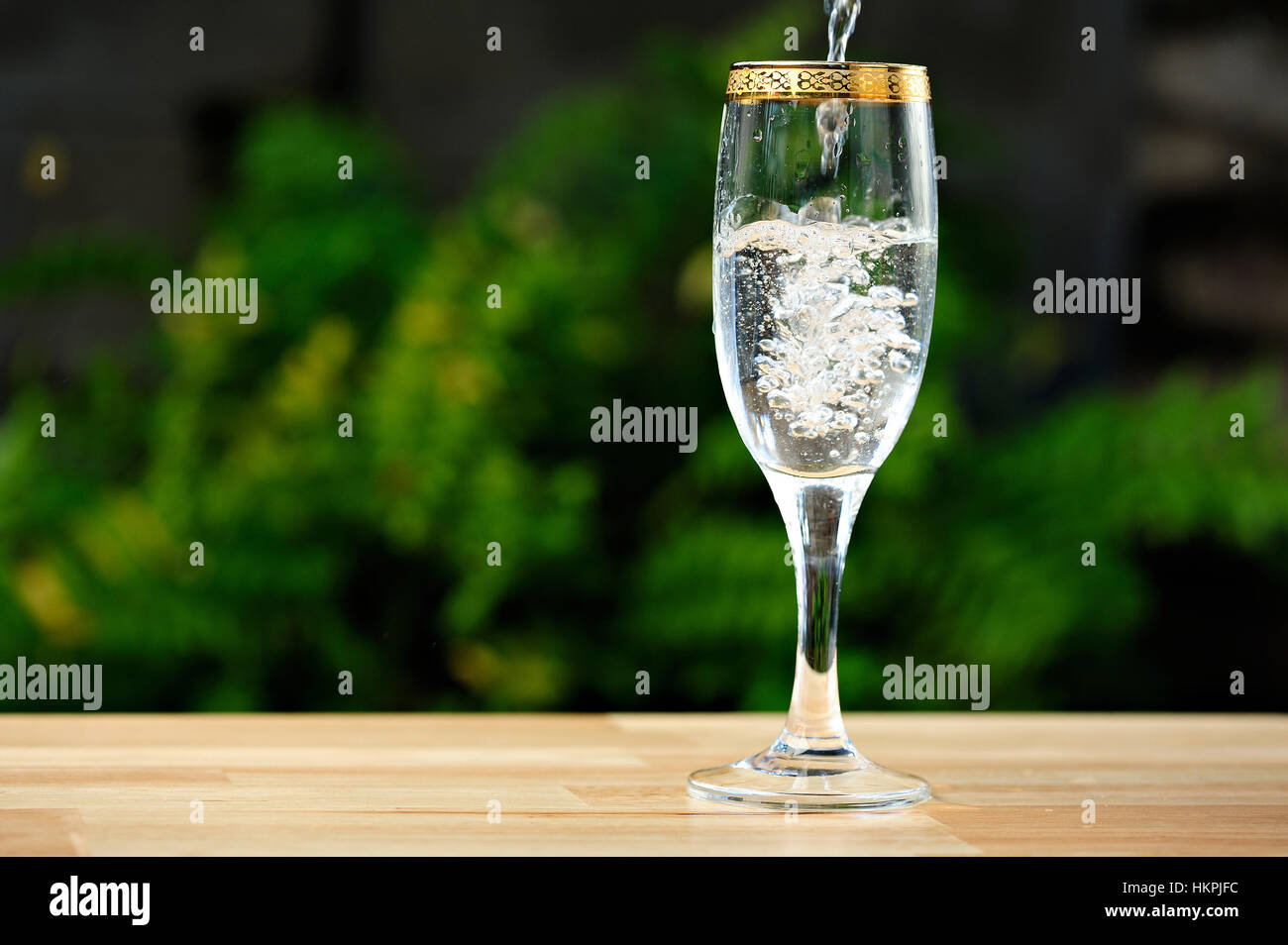 pouring white wine on tall glass with gold line Stock Photo