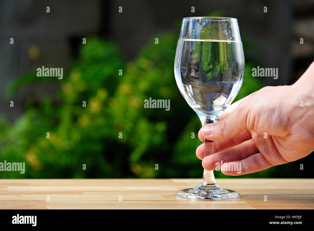 tall glass with water on hand in green park background Stock Photo Alamy