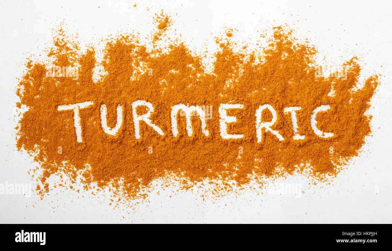 Turmeric powder sprinkled on a natural background. The word turmeric is spelled out across the powdered surface. Stock Photo